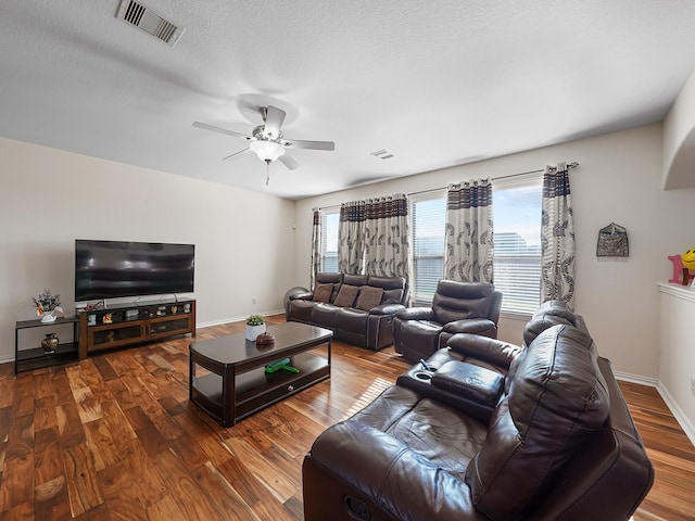 living area with a textured ceiling, wood finished floors, a ceiling fan, visible vents, and baseboards