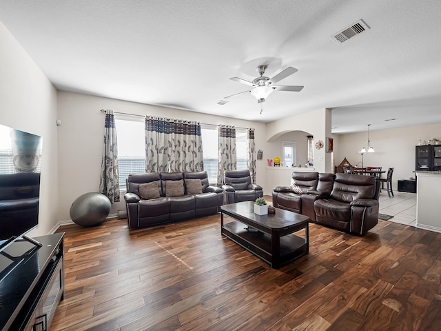 living area with visible vents, arched walkways, ceiling fan, wood finished floors, and a textured ceiling