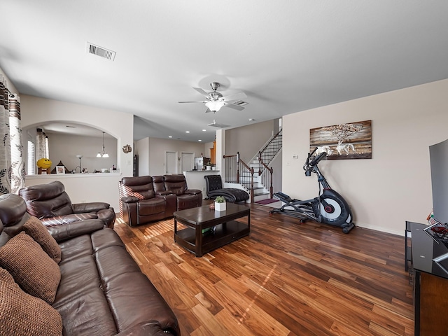 living area featuring arched walkways, visible vents, stairway, a ceiling fan, and wood finished floors