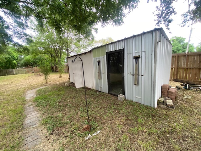 view of outdoor structure featuring fence and an outbuilding