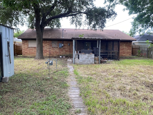 rear view of house featuring brick siding and fence