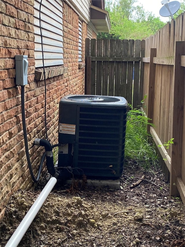 exterior details featuring fence, central AC, and brick siding