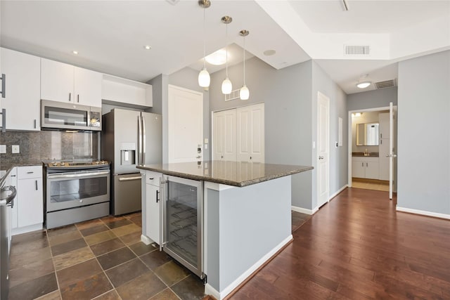 kitchen featuring visible vents, white cabinets, wine cooler, stainless steel appliances, and backsplash