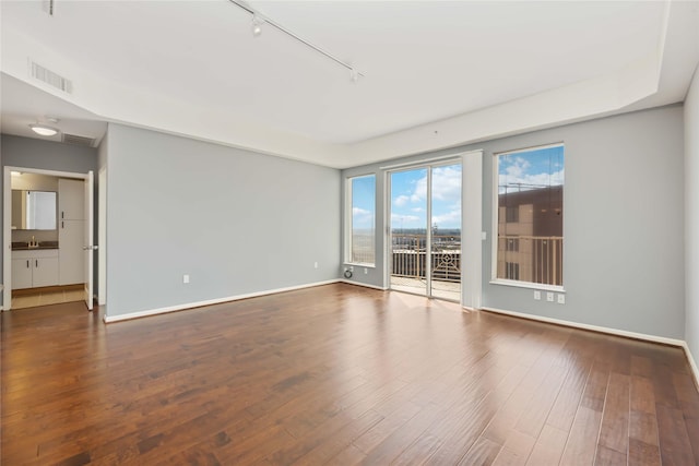 spare room featuring baseboards, visible vents, and dark wood-type flooring