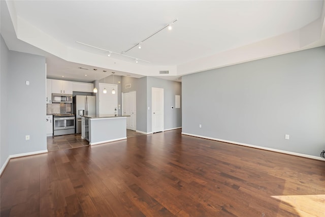 unfurnished living room with baseboards, track lighting, visible vents, and dark wood-style flooring