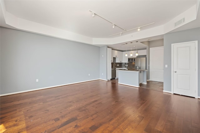 unfurnished living room featuring dark wood finished floors, visible vents, and baseboards