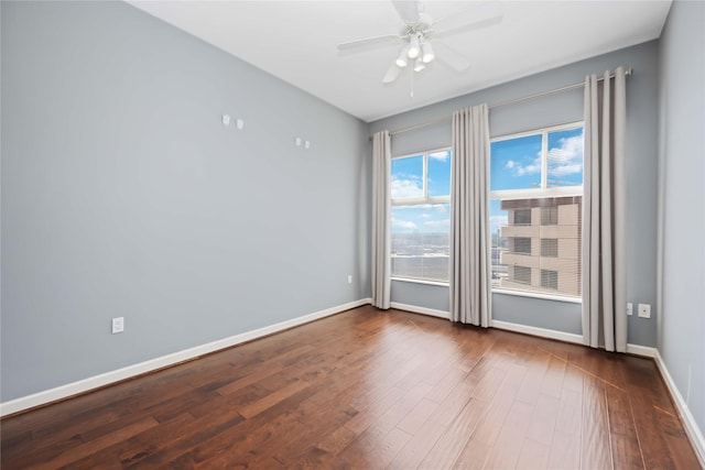 empty room with a ceiling fan, baseboards, and wood finished floors