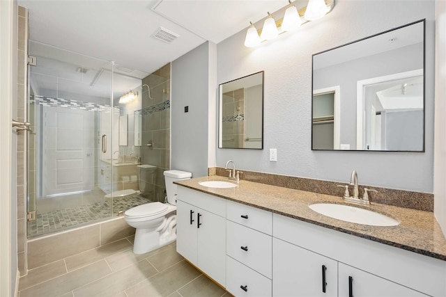 bathroom with visible vents, double vanity, a sink, and toilet