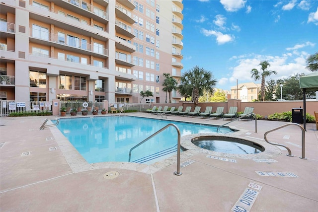 pool featuring a community hot tub, a patio area, and fence