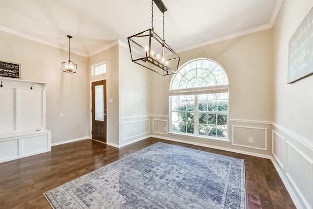 entrance foyer featuring a decorative wall, a notable chandelier, wood finished floors, ornamental molding, and wainscoting