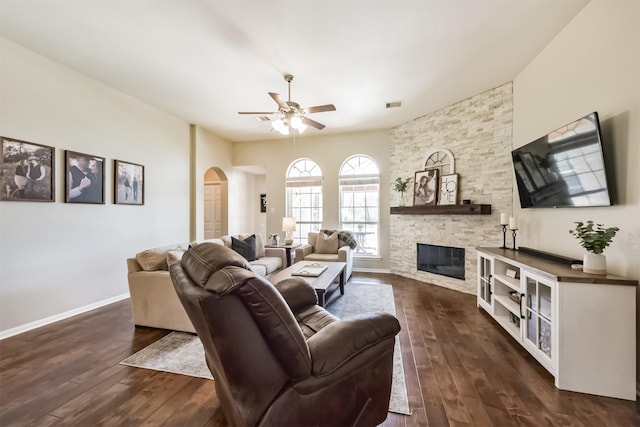 living room featuring a fireplace, visible vents, arched walkways, and dark wood finished floors