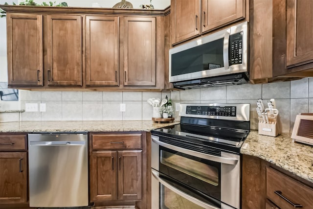 kitchen with stainless steel appliances, light stone counters, and decorative backsplash