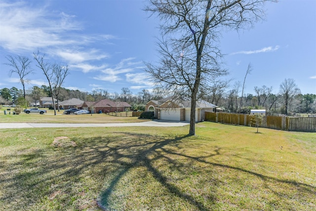 view of yard with concrete driveway, fence, and an attached garage