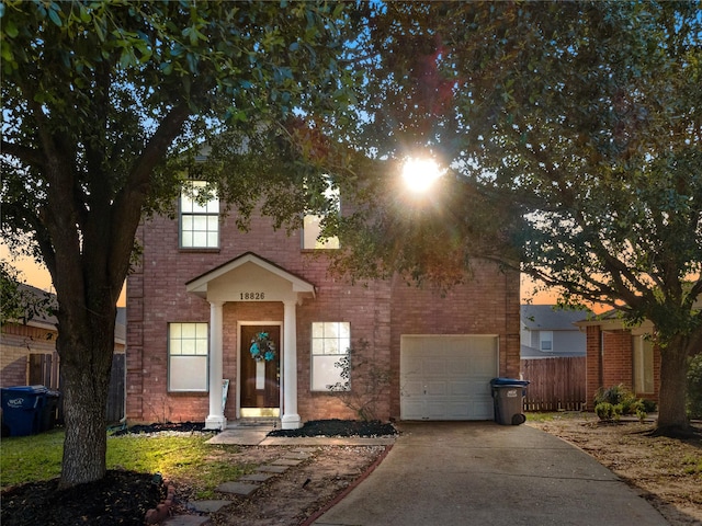 view of front of home with a garage, concrete driveway, brick siding, and fence