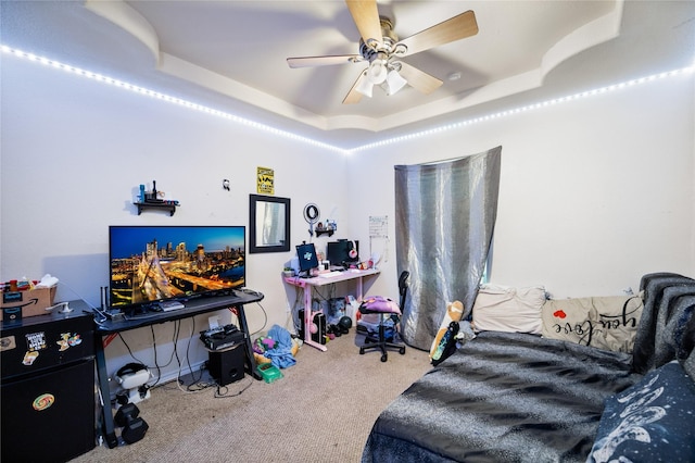 bedroom with ceiling fan, a tray ceiling, and carpet flooring