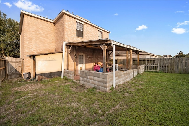 back of property featuring a fenced backyard, a yard, and brick siding