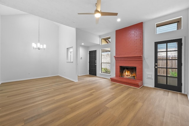 unfurnished living room featuring light wood-type flooring, a wealth of natural light, and a brick fireplace