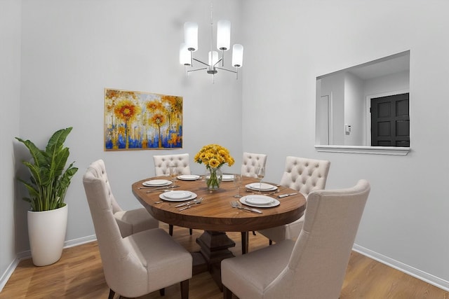 dining room featuring a chandelier, baseboards, and wood finished floors