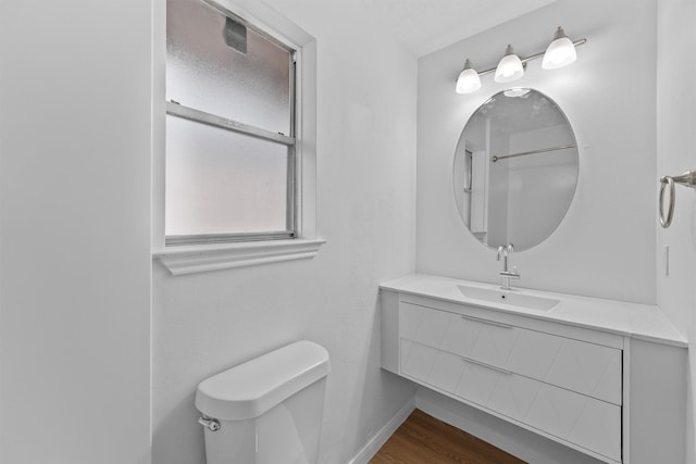 bathroom featuring toilet, baseboards, wood finished floors, and vanity