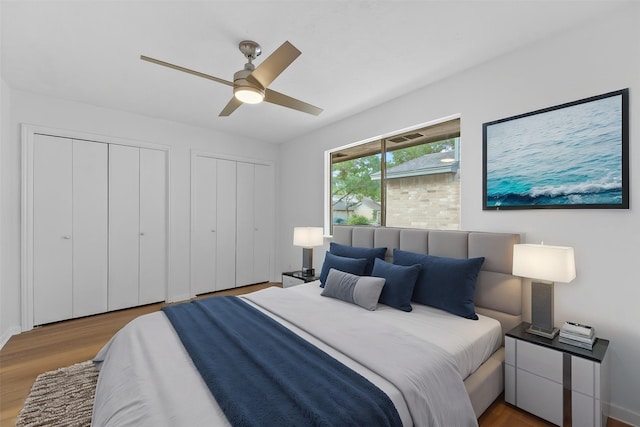 bedroom with wood finished floors, two closets, and a ceiling fan