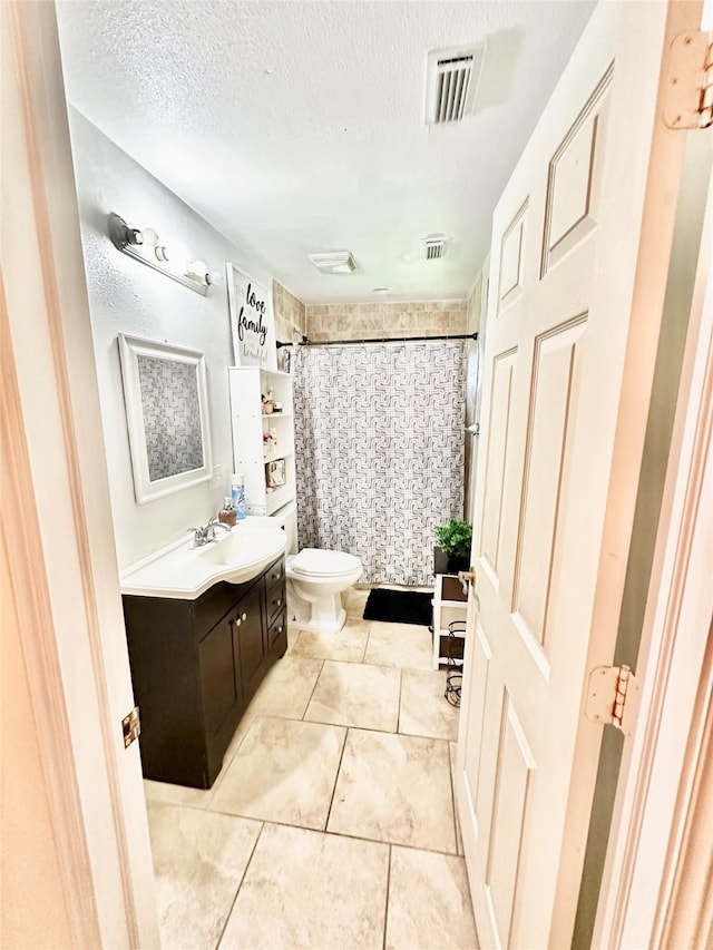 full bathroom with a textured ceiling, toilet, vanity, and visible vents