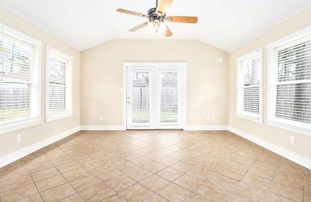 empty room featuring vaulted ceiling, ceiling fan, light tile patterned floors, and baseboards