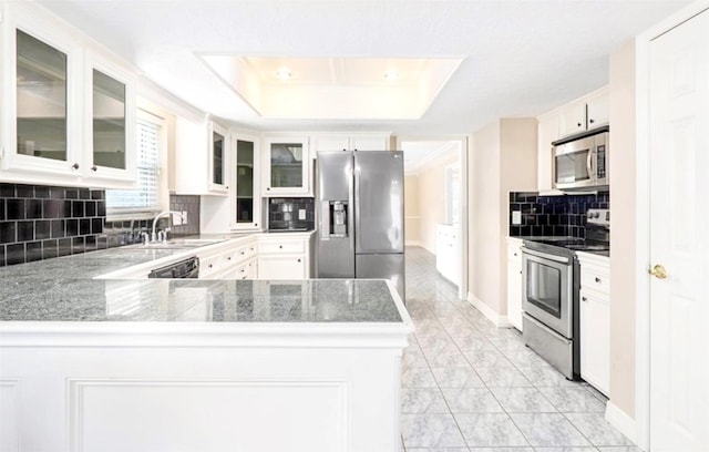 kitchen with a peninsula, a sink, marble finish floor, appliances with stainless steel finishes, and a raised ceiling