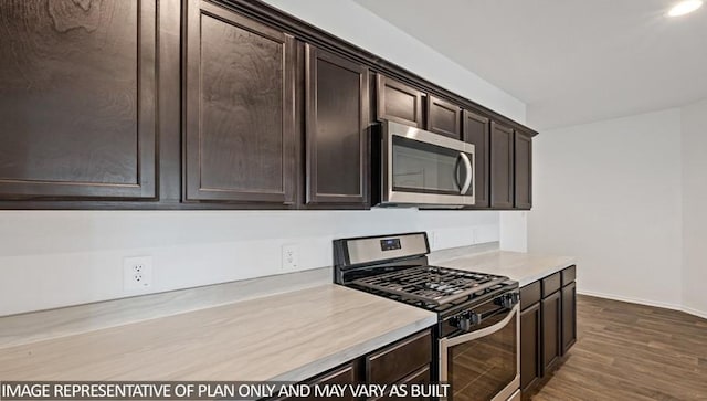 kitchen featuring dark brown cabinetry, stainless steel appliances, baseboards, light countertops, and dark wood-style floors