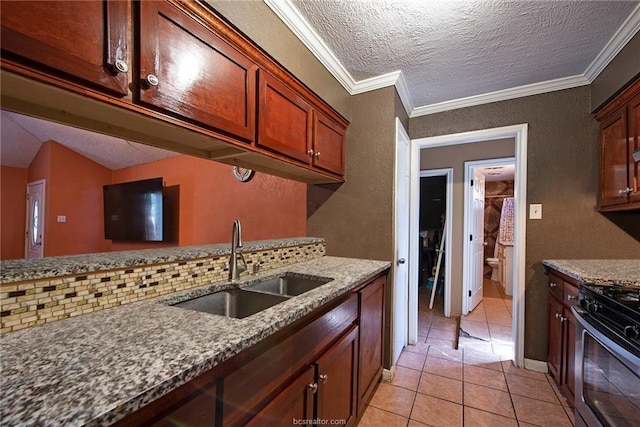 kitchen with stone countertops, a sink, backsplash, gas range, and crown molding