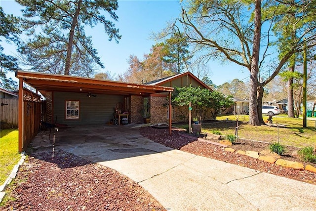 view of front facade featuring a carport, fence, concrete driveway, and brick siding