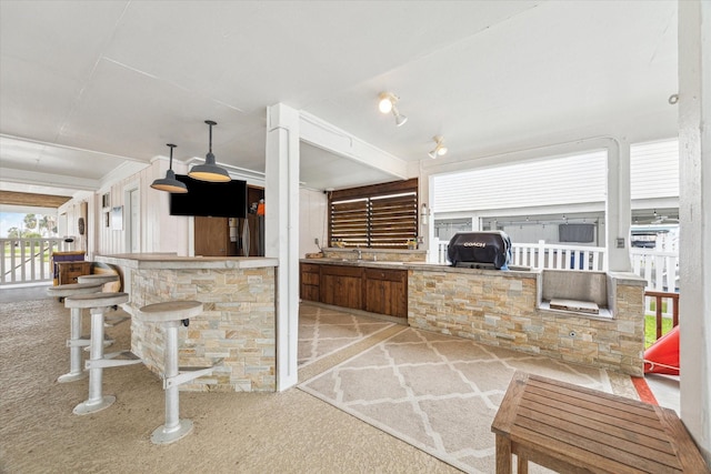 interior space with a grill, an outdoor kitchen, a sink, and outdoor wet bar