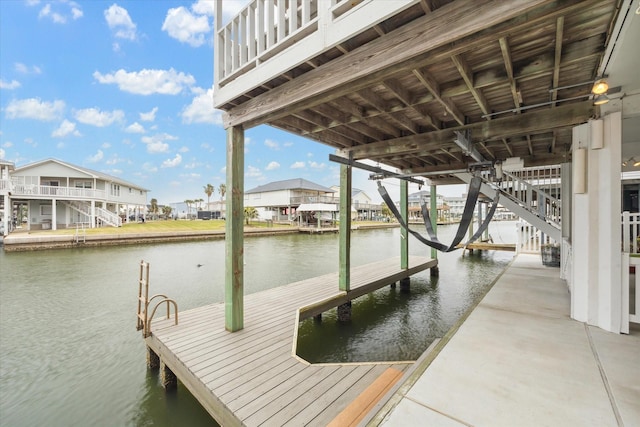 view of dock featuring a water view, boat lift, and a residential view