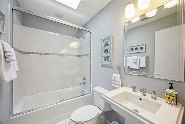 bathroom with bath / shower combo with glass door, a skylight, a sink, and toilet