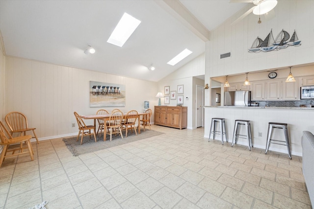 dining area featuring a skylight, baseboards, visible vents, high vaulted ceiling, and beam ceiling