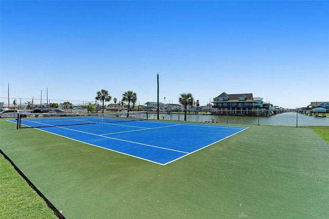 view of sport court with a water view and fence