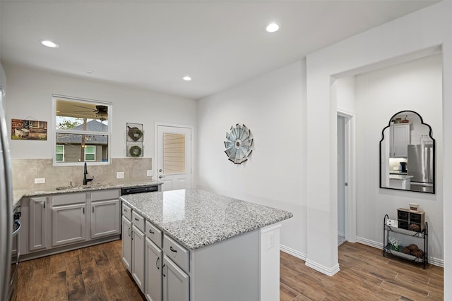 kitchen featuring dark wood-style floors, gray cabinets, freestanding refrigerator, a sink, and a kitchen island