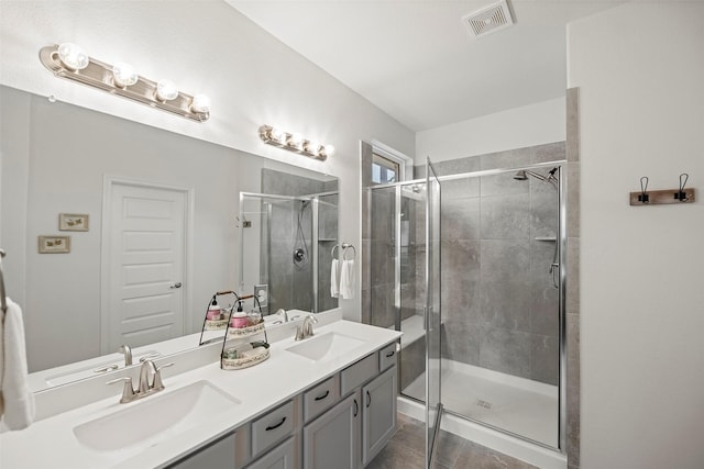 bathroom with double vanity, a stall shower, visible vents, and a sink