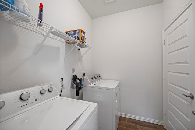 clothes washing area with laundry area, dark wood finished floors, washer and clothes dryer, and baseboards