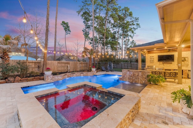 pool at dusk featuring a pool with connected hot tub, a fenced backyard, and a patio