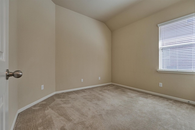 spare room featuring carpet floors, lofted ceiling, and baseboards