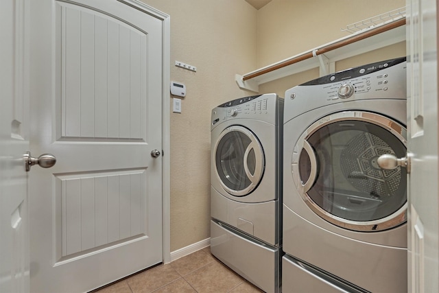 laundry area featuring laundry area, light tile patterned floors, baseboards, and washing machine and clothes dryer