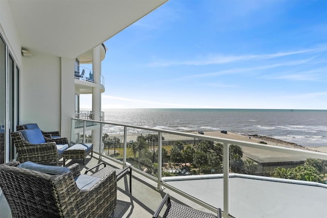 balcony with a water view and a view of the beach