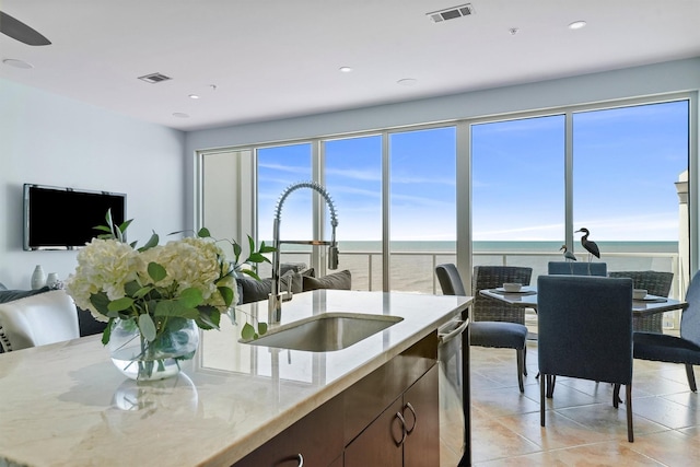 kitchen featuring light stone countertops, light tile patterned floors, visible vents, and a sink