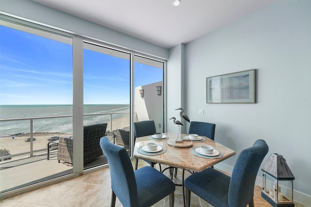 dining area featuring recessed lighting, baseboards, a beach view, a water view, and light tile patterned flooring