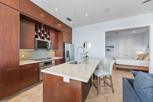 kitchen with a breakfast bar area, stainless steel appliances, a sink, visible vents, and tasteful backsplash