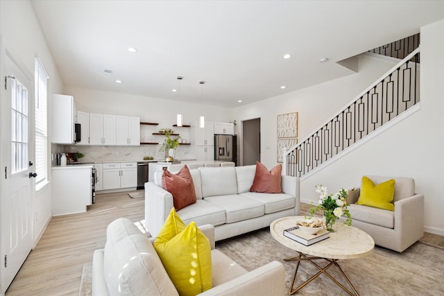 living room featuring light wood-style floors, visible vents, stairway, and recessed lighting