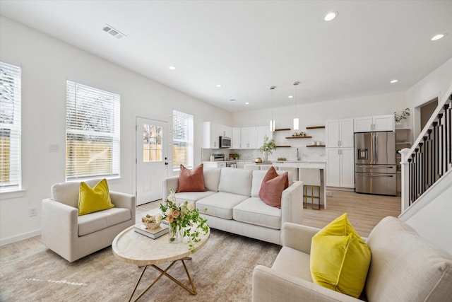 living area with light wood finished floors, baseboards, visible vents, stairs, and recessed lighting