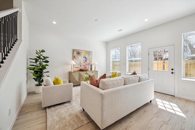 living room featuring light wood finished floors, baseboards, visible vents, stairway, and recessed lighting