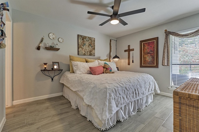 bedroom with light wood-type flooring, a ceiling fan, and baseboards