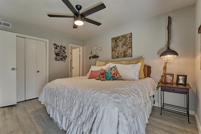 bedroom featuring light wood-type flooring, a closet, visible vents, and ceiling fan